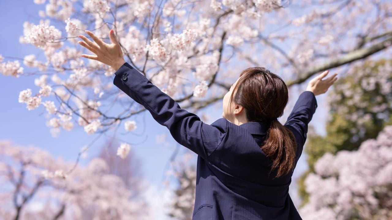 桜の木の下で大きく手を広げる女性