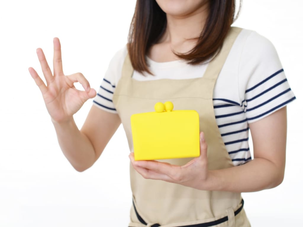 財布を片手にＯＫサインをする女性