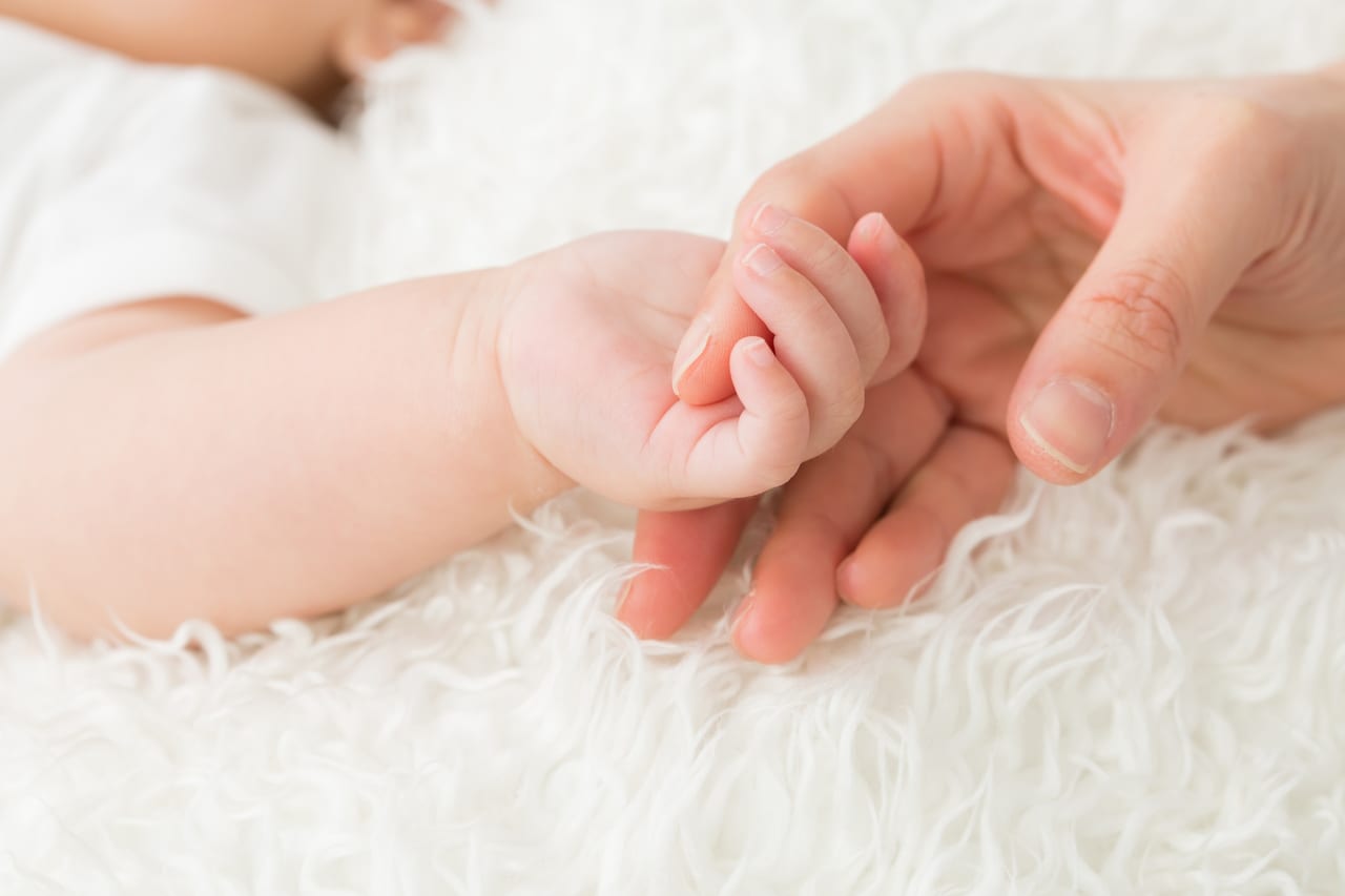 赤ちゃんと手をつなぐ女性の手